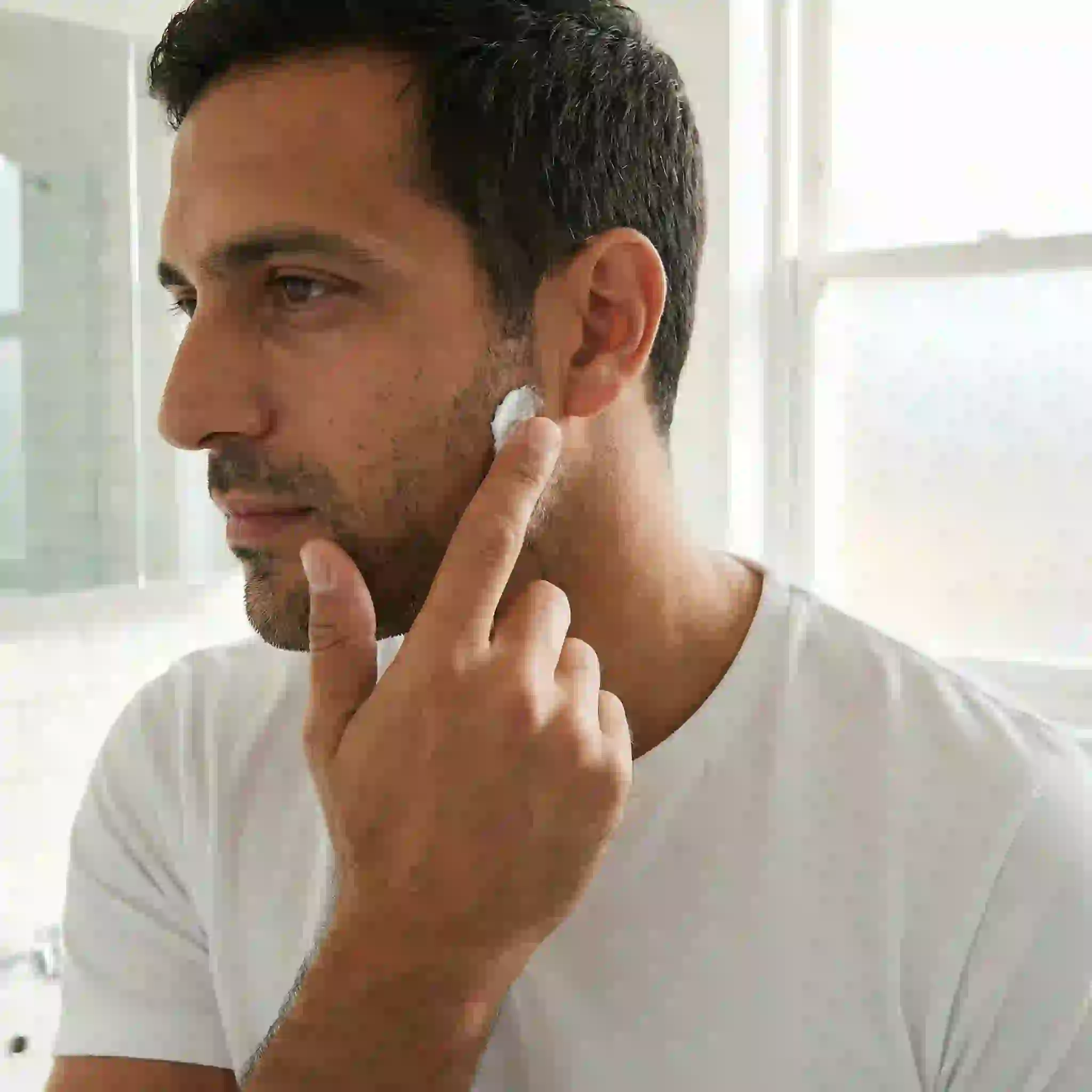 A man performing a patch test on his inner arm before using beard removal cream on his face, a crucial safety step to check for allergic reactions or skin sensitivity and ensure a safe experience.