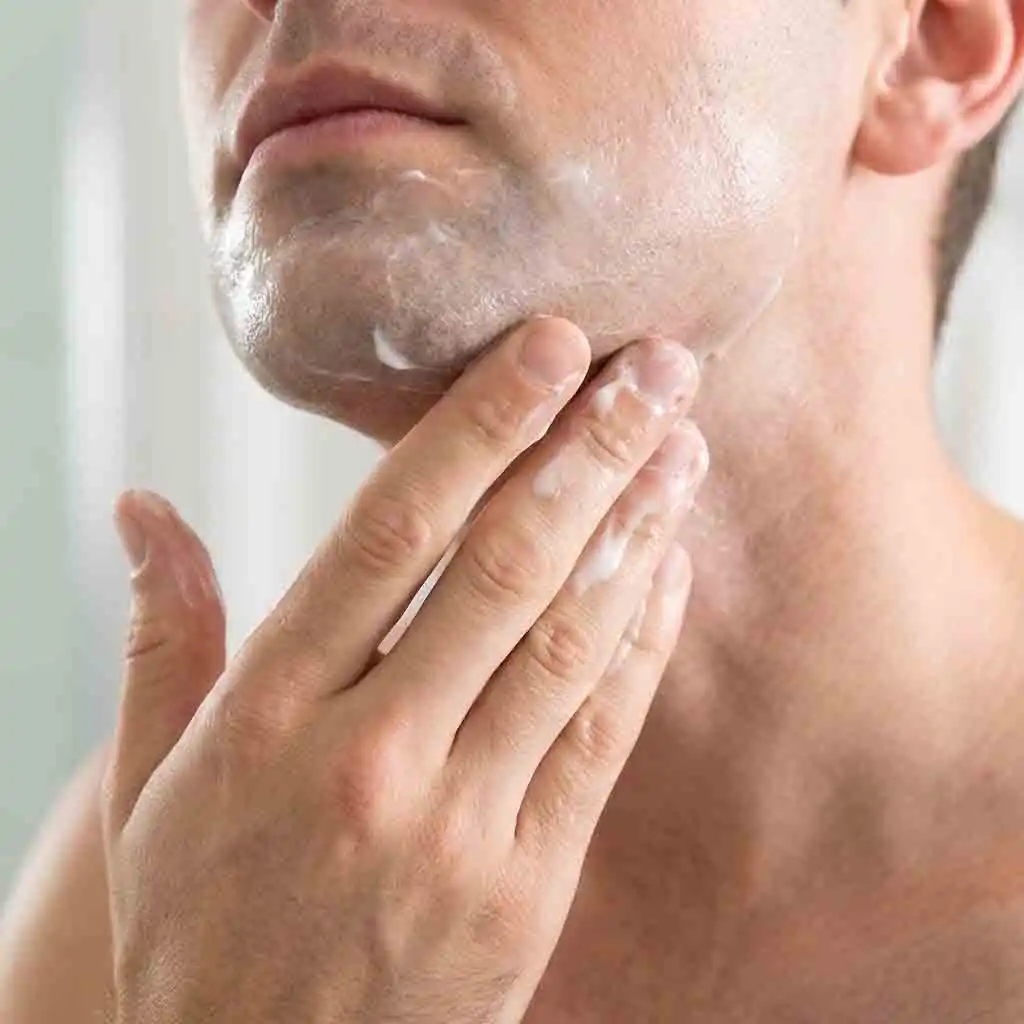 Gently applying a hydrating alcohol-free aftershave balm to the neck area, ensuring the skin remains moisturized and protected as the final part of how to get the cleanest shave routine.