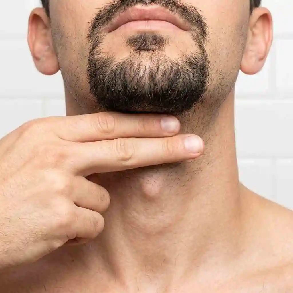 A diagram illustrating the two-finger rule to find the perfect neckline position, a professional secret that helps anyone learning how to shave into a goatee avoid common mistakes like cutting the neckline too high.